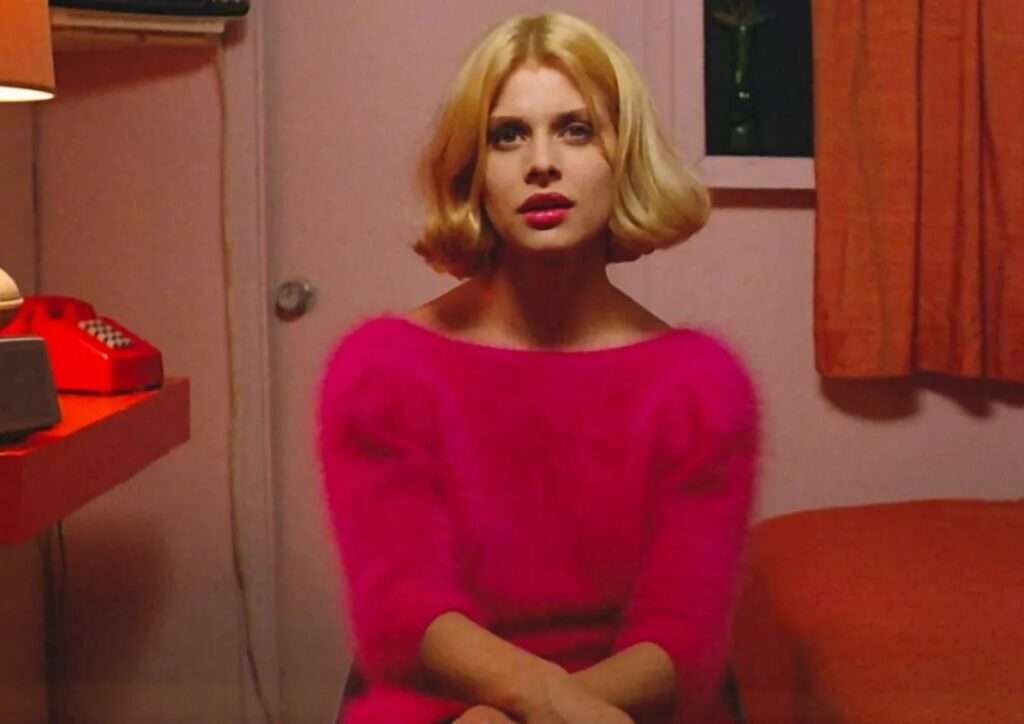 Une femme blonde en pull rose